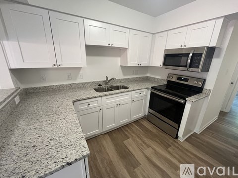 A kitchen with white cabinets and a granite countertop.