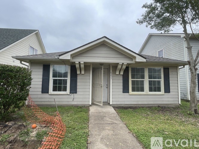 A house with a grey siding and a white door is for sale.