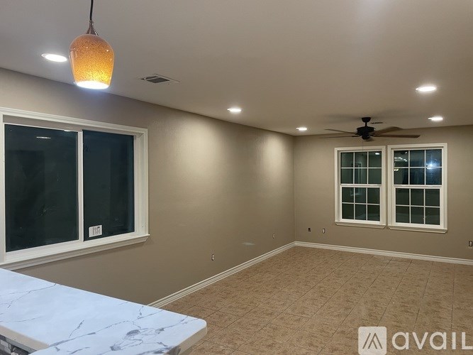 A room with a ceiling fan and two windows.