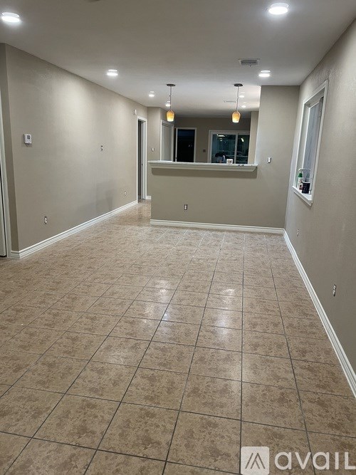 A spacious room with tiled flooring and a bar area.
