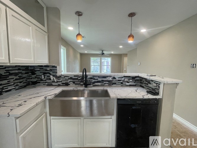 A kitchen with a marble countertop and a stainless steel dishwasher.