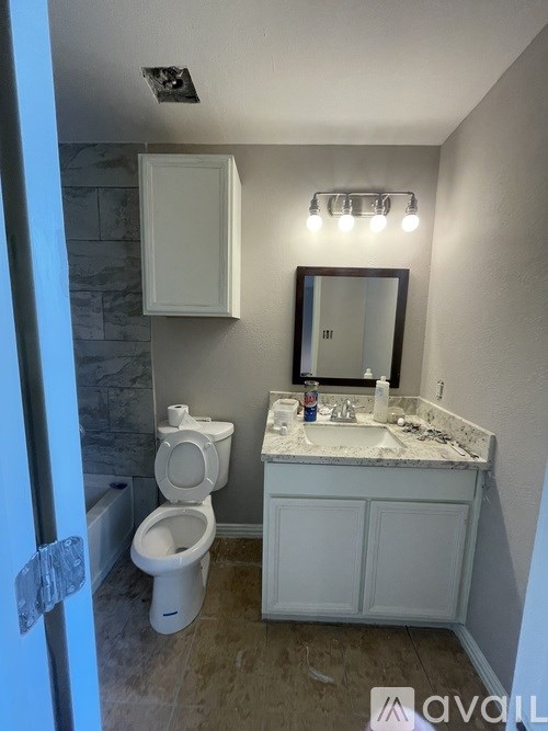A bathroom with a toilet, sink, and mirror.