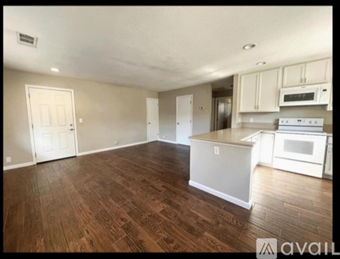A kitchen with white appliances and wooden floors.