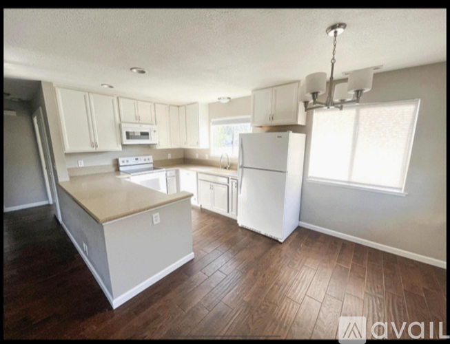 A kitchen with white appliances and wooden floors.
