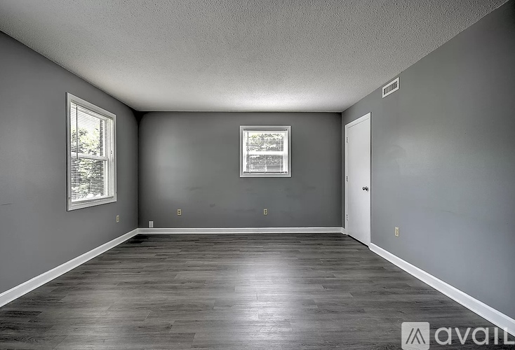 A spacious room with grey walls and wooden flooring.