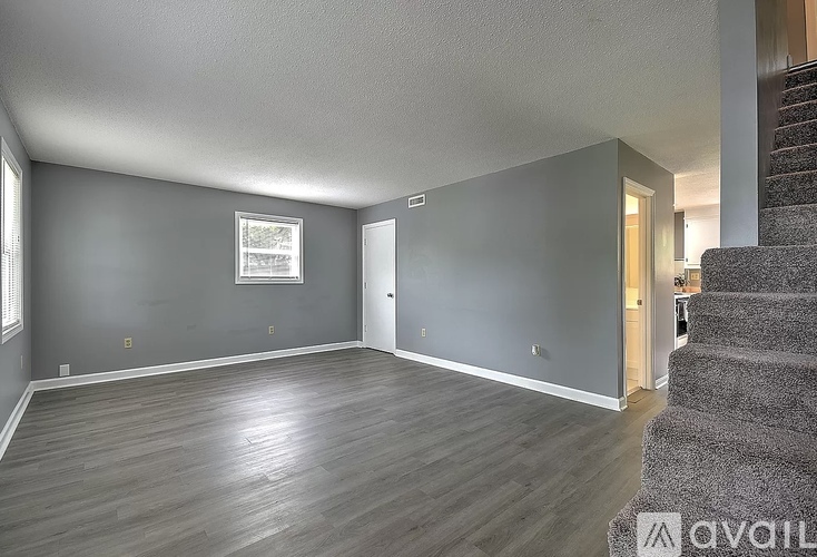 A spacious room with a staircase on the right side.
