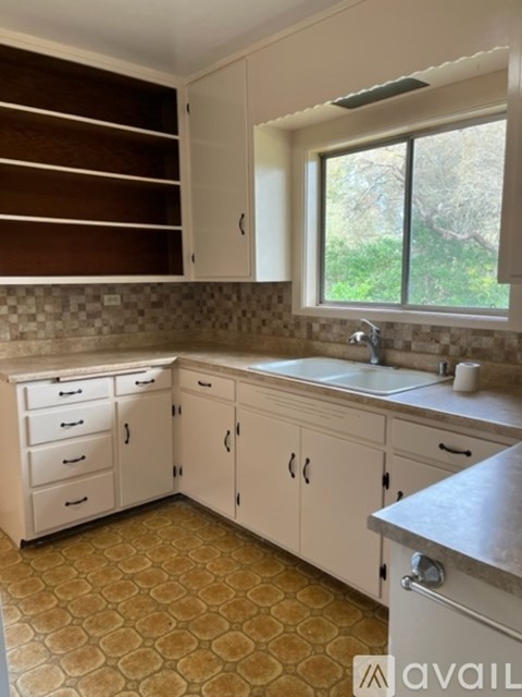 A kitchen with white cabinets and a tiled floor.