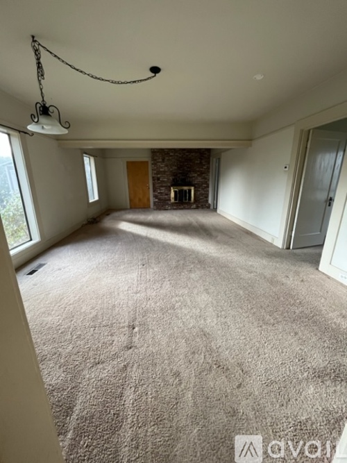 A spacious room with a carpeted floor and a chandelier hanging from the ceiling.