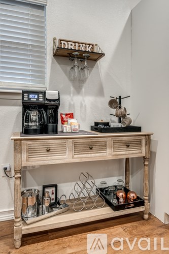 A wooden bar cart with a coffee machine and glasses on top.