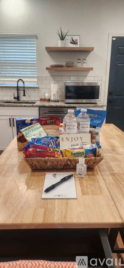 A wooden table with a basket of snacks and a bottle of water on it.