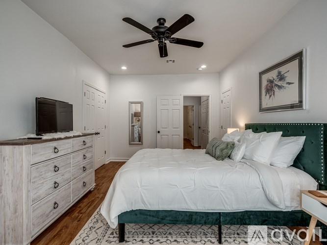 A bedroom with a large bed, a ceiling fan, and a TV on a cabinet.