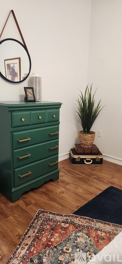 A green dresser with a mirror above it and a plant to the side.