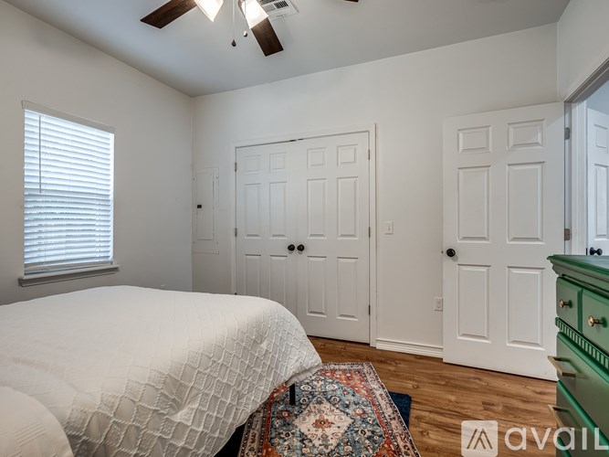 A bedroom with a bed, two doors, and a rug.
