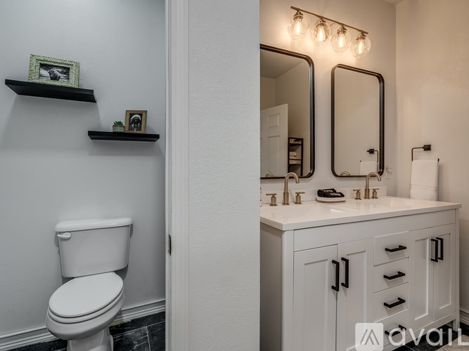 A white toilet sits next to a bathroom vanity with a mirror above it.