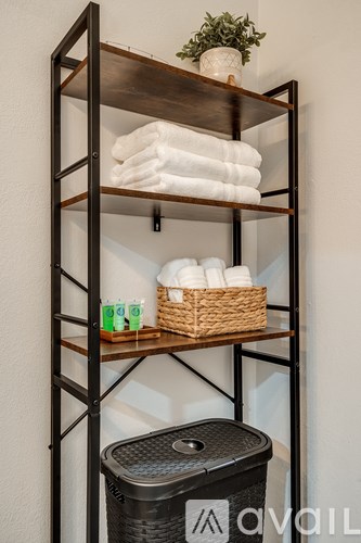 A shelf with towels, a basket, and cups.