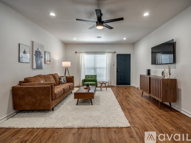A living room with a brown couch, a white rug, and a ceiling fan.
