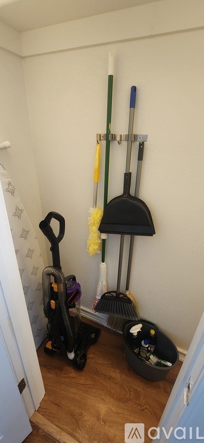 A white wall with a broom and a dustpan hanging on it.