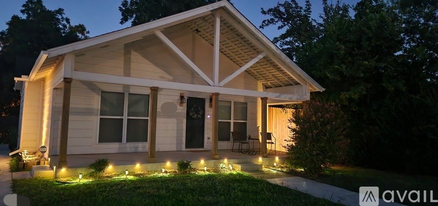 A house with a porch and lights on the grass.