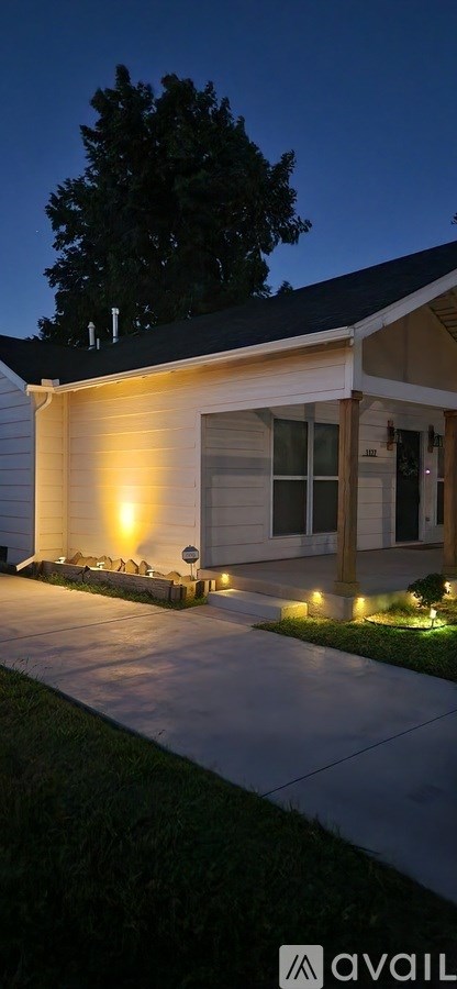A house with a lit up pathway leading to the front door.