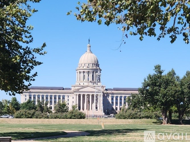 A large, white, domed building with columns is surrounded by trees.