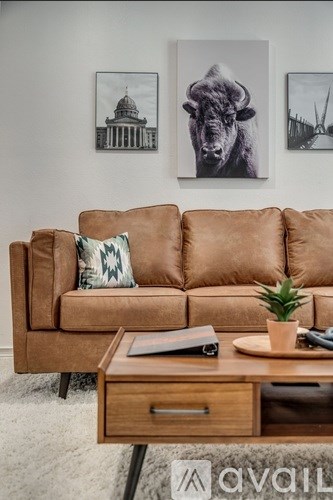 A tan couch with a green and white pillow and a wooden coffee table in front of it.