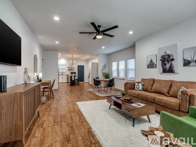 A living room with a brown couch and a white rug.
