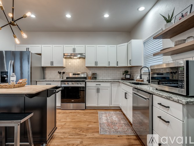 A modern kitchen with wooden floors and stainless steel appliances.