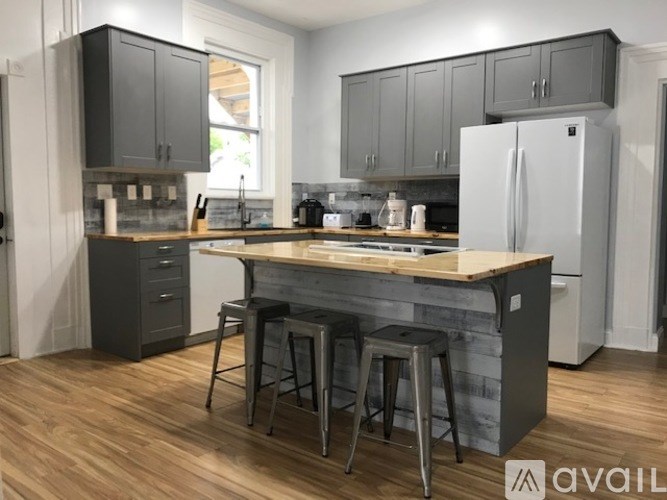 A kitchen with a wooden island and bar stools.