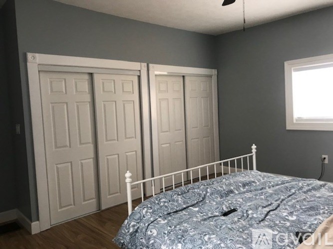 A bedroom with a bed, two doors, and a window.