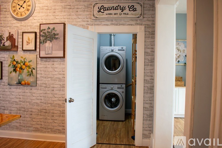 A bedroom with a large bed and a small white table with a lamp on it.