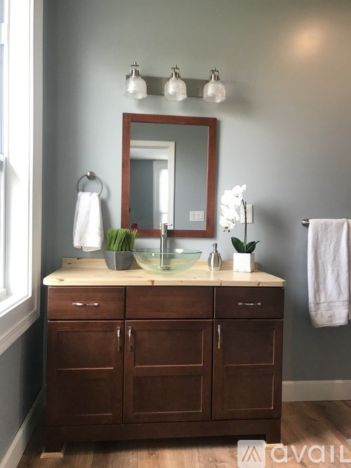 A bathroom with a wooden vanity and a mirror above it.