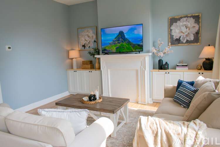 A living room with a white couch and wooden floors.