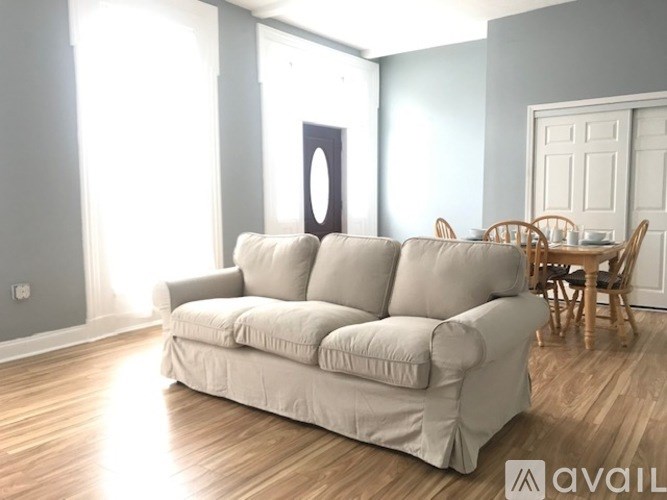 A living room with a white couch and wooden floors.