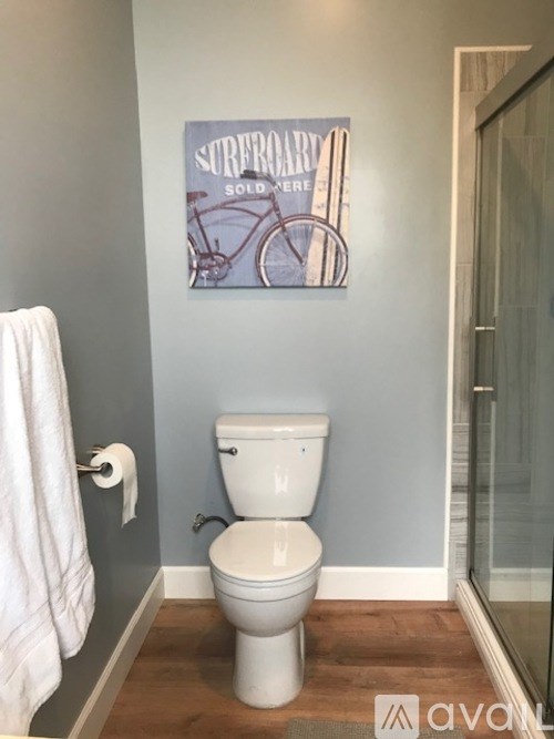 A white toilet in a bathroom with a poster of a bicycle on the wall.
