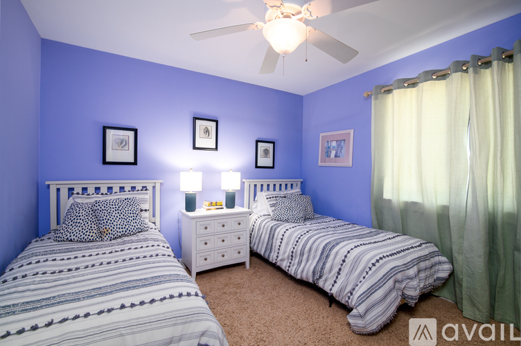 A bedroom with two beds, one with a white headboard and the other with a striped comforter.