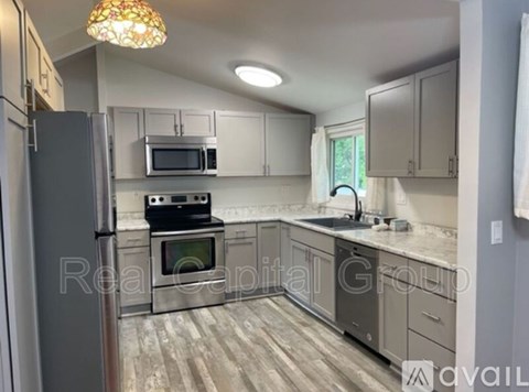 A kitchen with a refrigerator, microwave, oven, and cabinets.
