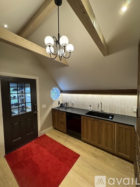 A kitchen with wooden cabinets and a red rug on the floor.