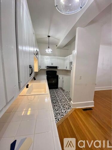 A kitchen with white cabinets and black and white tiled floor.