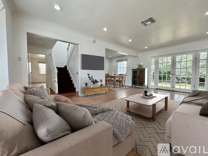 A living room with a couch, a coffee table, and a staircase.