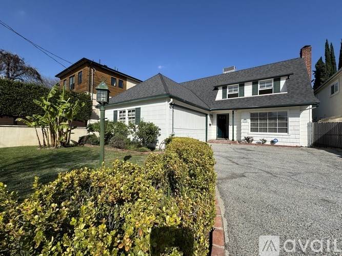 A house with a driveway and a hedge in front.