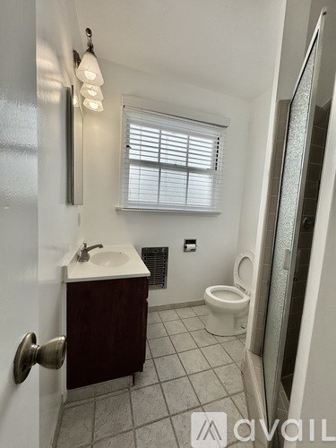 A small bathroom with a toilet, sink, and shower.