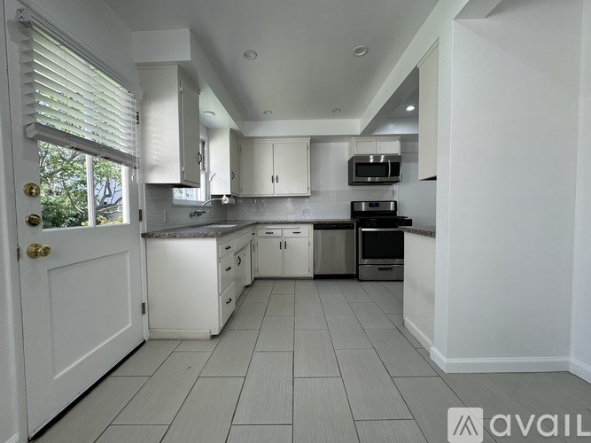 A kitchen with white cabinets and appliances is available for rent.