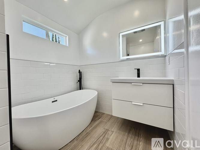 A white bathroom with a tub, sink, and mirror.