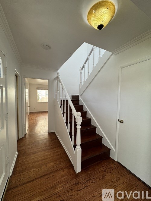 A long hallway with a staircase and a light on the ceiling.