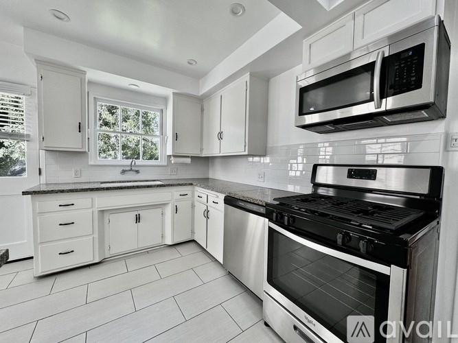A modern kitchen with a stainless steel oven and white cabinets.