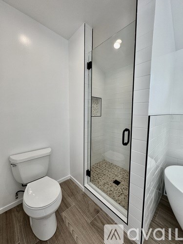 A white toilet sits in a bathroom next to a walk-in shower.