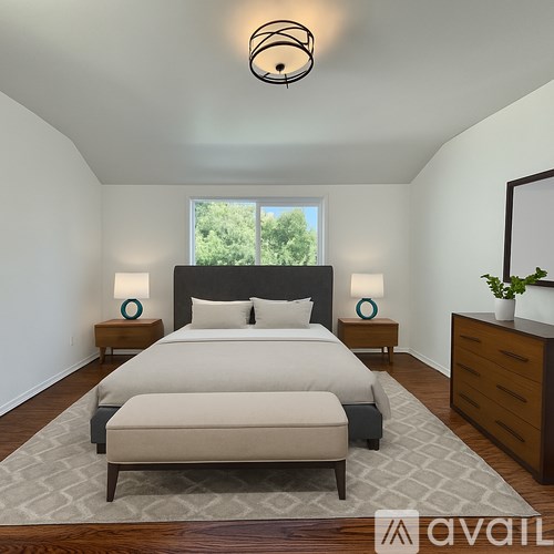 A bedroom with a large bed and a window overlooking trees.