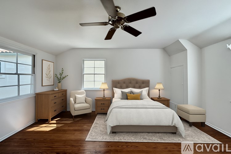 A bedroom with a large bed, a chair, a dresser, and a ceiling fan.