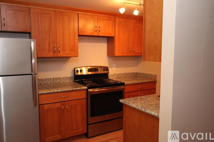A kitchen with wooden cabinets and a stainless steel refrigerator.
