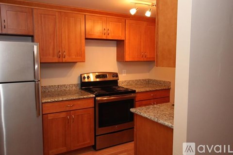 A kitchen with wooden cabinets and a stainless steel refrigerator.